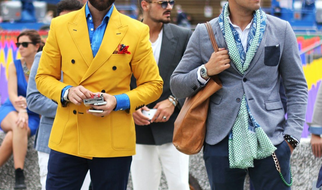 two man wearing yellow and grey suit jacket standing close together