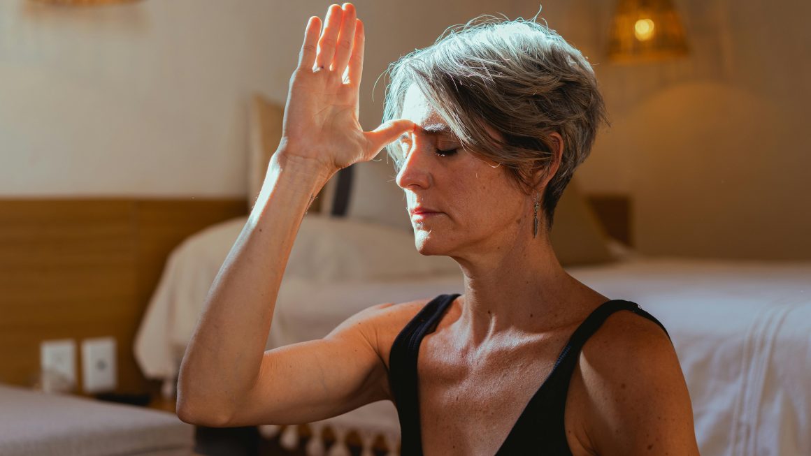 Serene elderly woman practicing yoga meditation indoors, symbolizing wellness and positive aging.